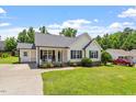Well-maintained home featuring a lush front lawn, covered porch with rocking chairs, and a private driveway at 65 Alcock Ln, Youngsville, NC 27596