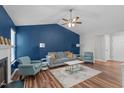 Living room showcasing blue walls, vaulted ceiling, fireplace, and hardwood floors at 700 Mossburn Ct, Fuquay Varina, NC 27526