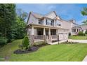 Two-story home with a covered porch and stone accents, complemented by a lush lawn and mature trees at 733 Bluffcreek Dr, Fuquay Varina, NC 27526