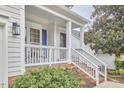 Inviting covered front porch with white railings and brick accents, perfect for relaxing outdoors at 102 Duxbury Dr, Cary, NC 27513