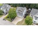 Aerial view of the home, featuring a large driveway and a wooded backyard with fire pit at 1144 Dexter Ridge Dr, Holly Springs, NC 27540