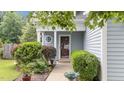 Inviting home entrance with a well-kept landscape, covered porch, and glass paneled door at 1144 Dexter Ridge Dr, Holly Springs, NC 27540