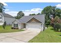 An inviting one-story home with a two-car garage, driveway and lush green lawn under a partly cloudy sky at 21 Cambridge Dr, Angier, NC 27501