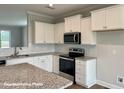 Modern kitchen featuring white cabinets, granite countertops, and stainless steel appliances at 348 Danube Dr, Zebulon, NC 27597