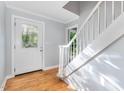 Bright entryway with hardwood floors, a decorative glass door, and staircase leading to the upper level at 5900 Holly Dr, Raleigh, NC 27616