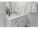 Bathroom featuring white cabinets, quartz counters, decorative mirror, towels, and flower decorations at 915 Ball Field Aly # 305, Cary, NC 27511