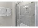 Modern walk-in shower with gray tiling, glass door, and convenient recessed shelving for toiletries at 915 Ball Field Aly # 305, Cary, NC 27511