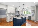 Bright kitchen featuring a navy blue island, white cabinets, stainless steel appliances, and hardwood floors at 11124 Penderwood Ct, Raleigh, NC 27617