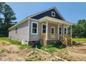Inviting home exterior featuring gray siding, a covered porch, and manicured landscaping at 213 Maye St, Dunn, NC 28334