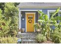 Close-up of the charming yellow front door with a wreath, blue siding, and stone steps at 216 Northwood Cir, Durham, NC 27701