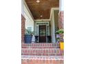 Inviting front porch with brick accents, decorative plants, and a stylish front door at 221 Grantwood Dr, Holly Springs, NC 27540