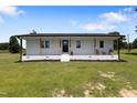 Charming front porch with wooden columns, a sleek front door, and well manicured garden beds at 224 Grameta Ln, Lillington, NC 27546