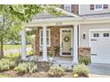 Inviting front porch featuring stone accents, white columns and manicured garden at 418 Magna Dr, Durham, NC 27703