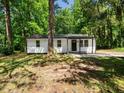 Charming single story home with light colored siding, dark trim, and inviting front porch nestled amongst mature trees at 4428 W West River Rd, Franklinton, NC 27525