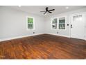 Bright living room showcasing hardwood floors, large windows, and a ceiling fan for comfort at 4428 W West River Rd, Franklinton, NC 27525