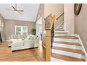 Cozy living room featuring hardwood floors, a ceiling fan, and staircase with decorative iron spindles at 5301 Denmead Way, Raleigh, NC 27613