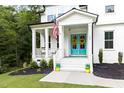 Inviting front porch with American flag, bright blue double doors adorned with wreaths, and colorful potted plants at 720 The Parks Dr, Pittsboro, NC 27312