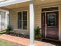 Charming front porch featuring a decorative door, brick floor, and seating area with ferns at 103 Aisling Ct, Cary, NC 27513