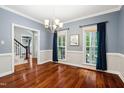Dining room features hardwood floors, modern chandelier, and windows with blue curtains at 11619 Appaloosa W Run, Raleigh, NC 27613