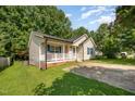 Exterior view of charming single-story home with a covered porch, front lawn, and mature trees at 1261 Grovewood Dr, Clayton, NC 27520