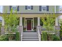 Inviting front porch with stairway, brick columns, white railings, and potted plants next to a deep red front door at 149 N Serenity Hill Cir, Chapel Hill, NC 27516