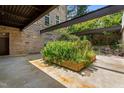 View of the patio with stone and brick walls, modern steel beam pergola, and greenery at 1500 River Mill Dr # 101, Wake Forest, NC 27587