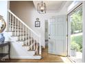 Inviting foyer featuring hardwood floors, staircase, elegant lighting and open front door at 18 Clearwater Dr, Durham, NC 27707