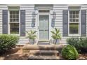 Close-up of a front porch with potted plants, brick steps, and gray trimmed windows at 18 Clearwater Dr, Durham, NC 27707