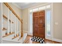 Welcoming entryway with hardwood floors, staircase, and a wooden front door with decorative glass panels at 1818 Misty Hollow Ln, Apex, NC 27502