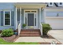 Inviting front porch with brick steps, white columns, and a gray front door with sidelights at 1818 Misty Hollow Ln, Apex, NC 27502