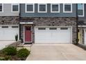 Close up of townhome exterior showing stone accents, garage, colorful front door, and manicured landscaping at 2006 Leo Dr, Apex, NC 27502