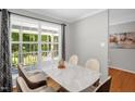 Bright dining area features a modern marble-topped table, hardwood floors, and a large window with scenic views at 211 Hills Of The Haw Rd, Pittsboro, NC 27312