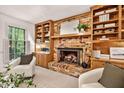 Comfortable living room with a brick fireplace, built-in shelves, and a large window overlooking the yard at 224 Fleming Dr, Durham, NC 27712