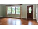 Bright living room featuring hardwood floors, large windows, and a classic front door at 2440 Gardner Holt Rd, Burlington, NC 27215