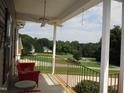 Relaxing front porch featuring a ceiling fan, a cozy red bench, and beautiful views of the yard at 3008 River Hill Ln, Burlington, NC 27217