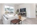 Bright living room featuring a cozy sofa, wooden coffee table, and large window at 5563 Henley Ridge Dr, Graham, NC 27253