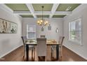 Bright dining room featuring hardwood floors, a coffered ceiling, and a contemporary chandelier over a dark table at 601 Minerva Dale Dr, Fuquay Varina, NC 27526