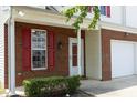 Close-up of the front entrance with brick exterior, red shutters, and well-manicured landscaping at 617 Woodson Dr, Clayton, NC 27527