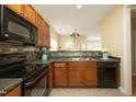 Functional kitchen featuring sleek, black appliances, warm wood cabinetry, and durable countertops at 617 Woodson Dr, Clayton, NC 27527