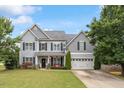 Charming two-story home with a well-manicured lawn, gray siding, and attached two car garage at 6901 Rex Rd, Holly Springs, NC 27540