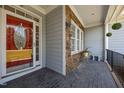 Inviting front porch featuring stone accents, a decorative red door, and seating area for guests at 6965 Ogburn Farms Dr, Willow Springs, NC 27592