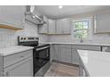 Modern kitchen with gray cabinets, white countertops, tile backsplash, and stainless steel appliances at 703 Whitsett Ave, Gibsonville, NC 27249