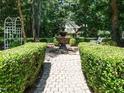 Lush backyard garden featuring stone walkway, fountain, bench, and mature trees at 8504 Carlton Oaks Dr, Wake Forest, NC 27587