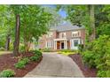 Stately brick home with lush landscaping and a curved driveway nestled among mature trees at 105 Bathgate Ln, Cary, NC 27513