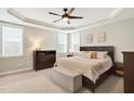 Cozy bedroom features a tray ceiling, ceiling fan, and large windows allowing for natural light at 108 Market Cross Ct, Holly Springs, NC 27540