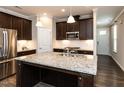 Modern kitchen with granite counters, stainless appliances, large island, and dark wood cabinets at 12421 Angel Vale Pl, Durham, NC 27703