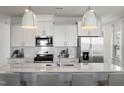 Modern kitchen featuring white cabinets, stainless steel appliances, and a quartz countertop island at 1472 Hasse Ave, Apex, NC 27502