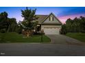 Charming single-story home with a well-manicured lawn, attached garage, and inviting curb appeal at twilight at 1705 Bodwin Ln, Apex, NC 27502