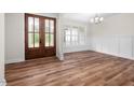 Bright dining room featuring wood floors, modern wainscoting, elegant lighting and charming double glass doors at 225 Whistlers Cv, Louisburg, NC 27549