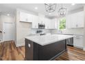 Modern kitchen with white cabinets, stainless steel appliances, white countertops and spacious center island at 225 Whistlers Cv, Louisburg, NC 27549